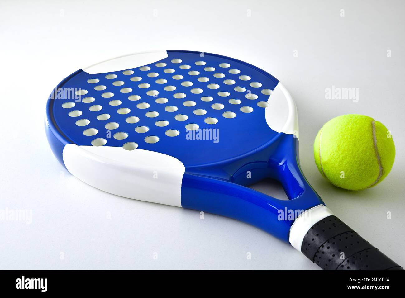 Padel racket on ball reflected on white table and white isolated background. Elevated view. Stock Photo