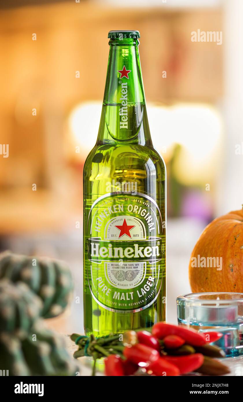 Glass green bottle of Heineken beer placed on counter against blurred background Stock Photo