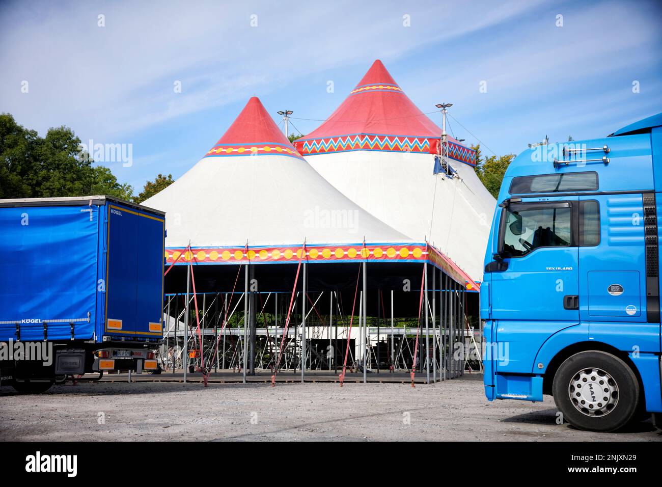 Ein Zirkuszelt das sich im Aufbau befindet vor dem LKWs stehen. Stock Photo