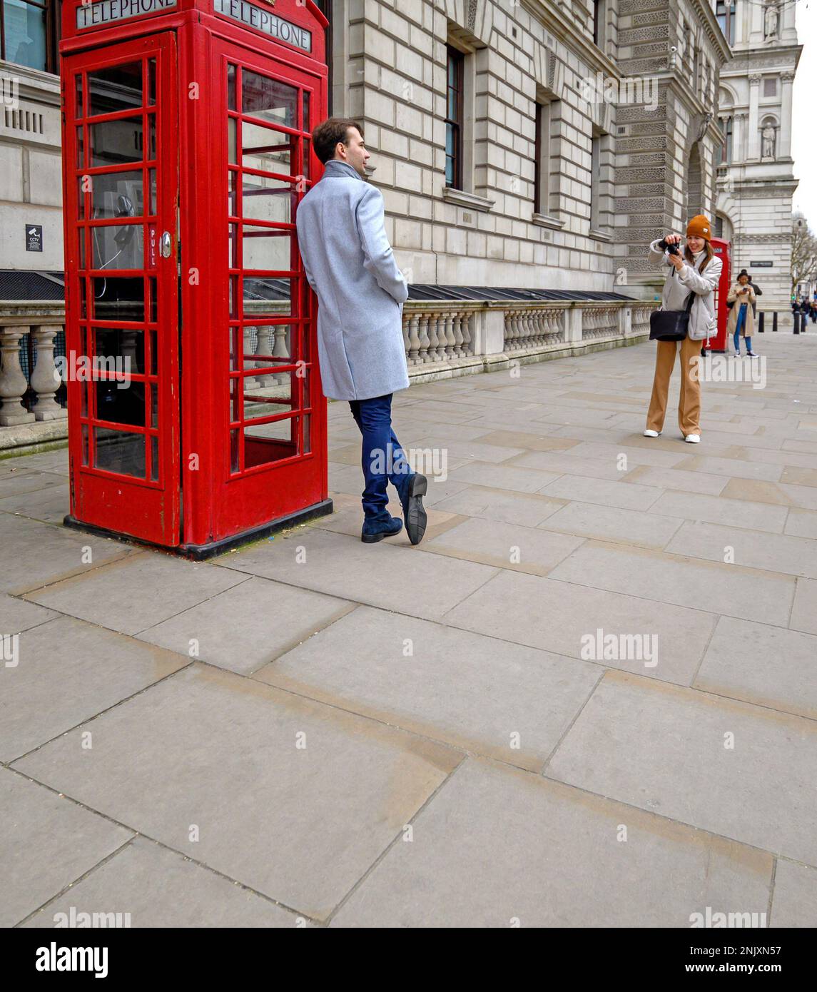 London, England, UK. Tourist posing for a photo by an iconic red