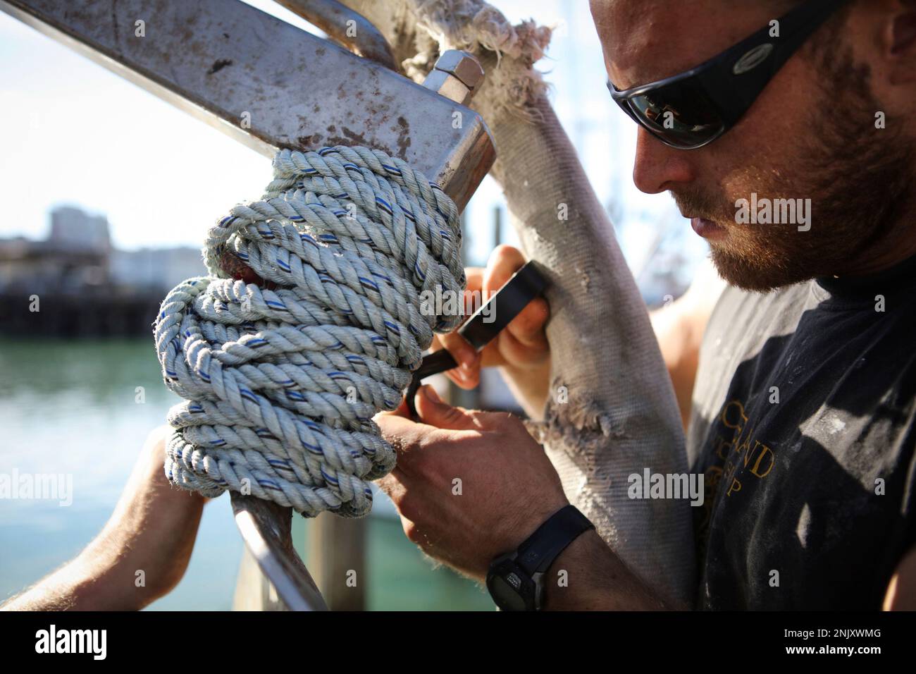 Peter Siegenthaler, a fisherman, puts rope around the top of a power ...