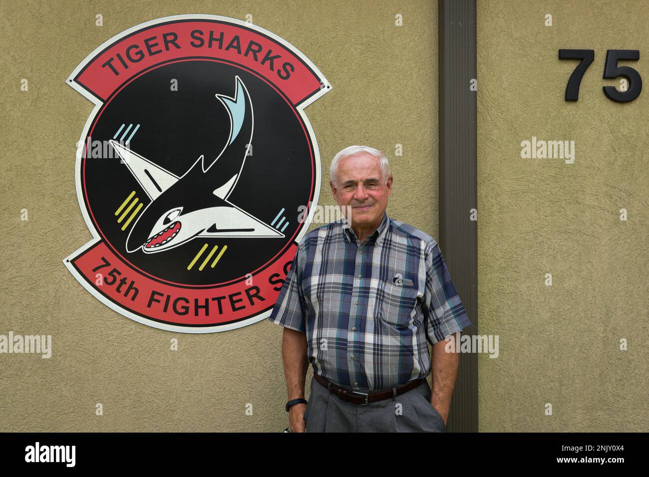 Ron Miller, son of Don Miller, an original Flying Tiger, poses in front of a 75th Fighter Squadron logo before a Heritage Hall ceremony at Moody Air Force Base, Georgia, Aug. 10, 2022. Miller’s father served as a pilot with the 75th FS during World War II. Stock Photo