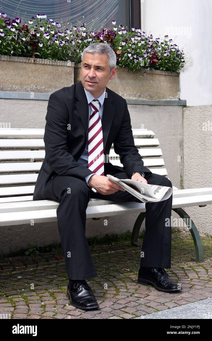 businessman sitting on a bench, reading business news Stock Photo