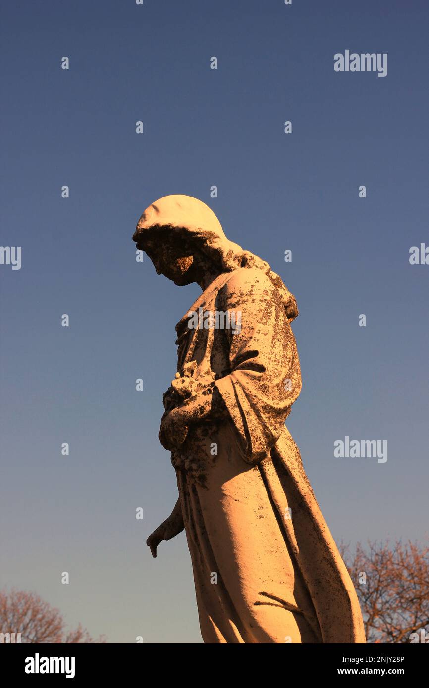 A statue of a young Virgin Mary holding her head down in sadness Stock ...
