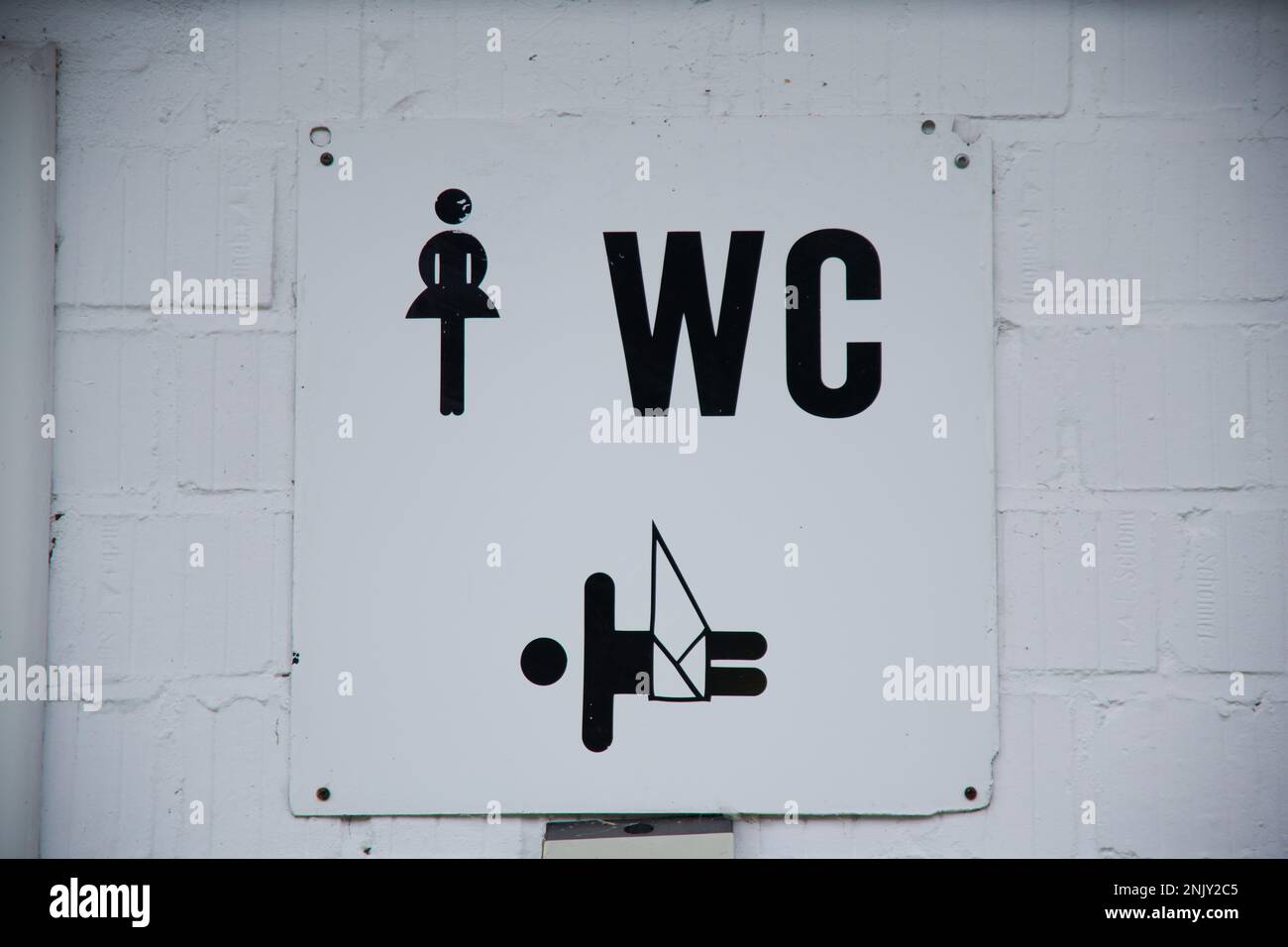 Auf einer weißen Wand hängt ein Hinweisschild auf dem der Hinweis für Damen WC mit Wickelmöglichkeit für Kleinkinder. Stock Photo