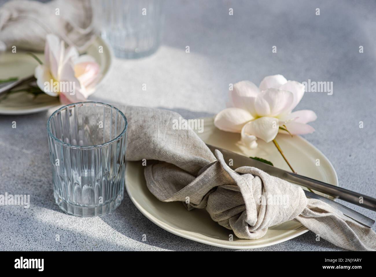 Table setting with white ceramic plates and white blooming roses Stock Photo