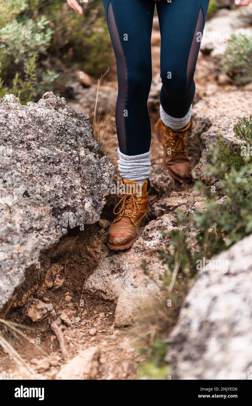 Crop anonymous female in leather boots and black leggings walking along