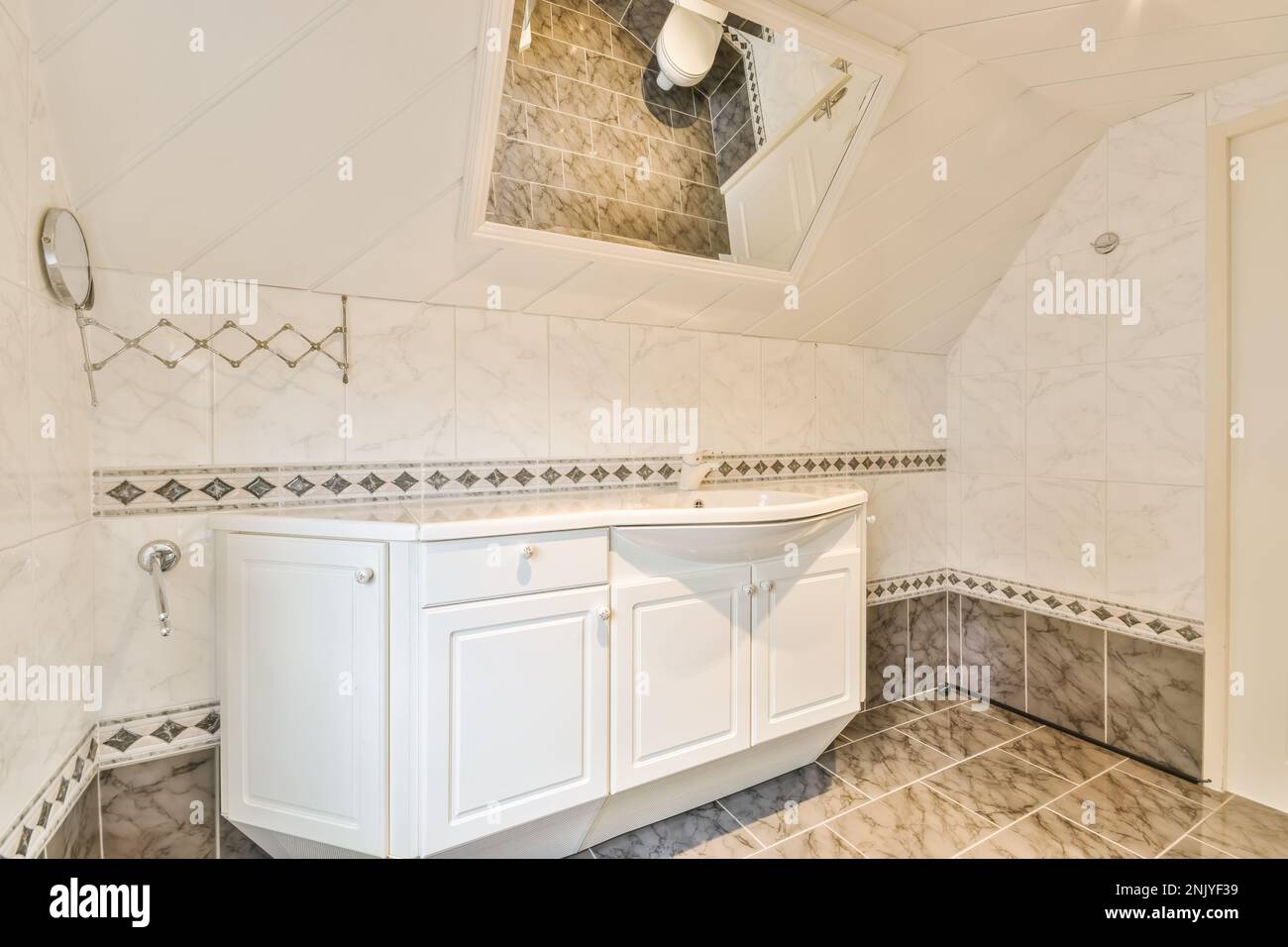 Interior design of light bathroom with white cabinet under the sink placed on marble tiled floor ...