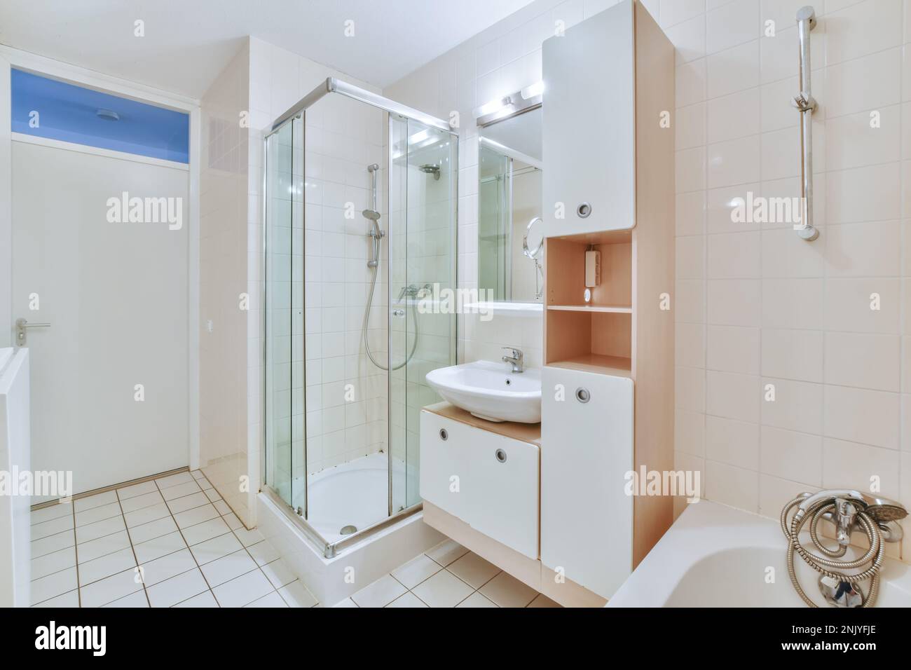 Interior design of bathroom with bathtub placed near vanity unit under