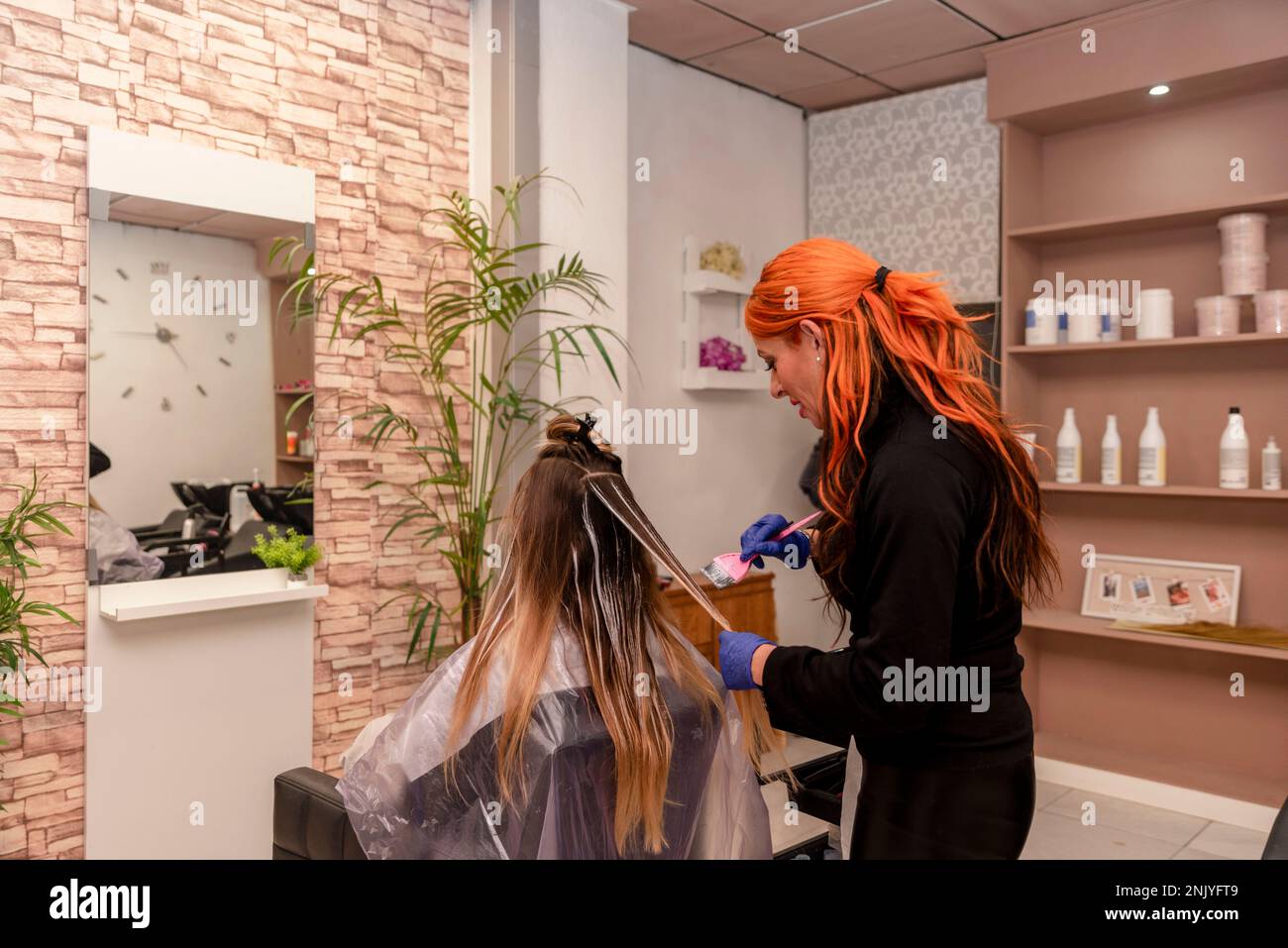 Side view happy female hairdresser in latex gloves dying hair of
