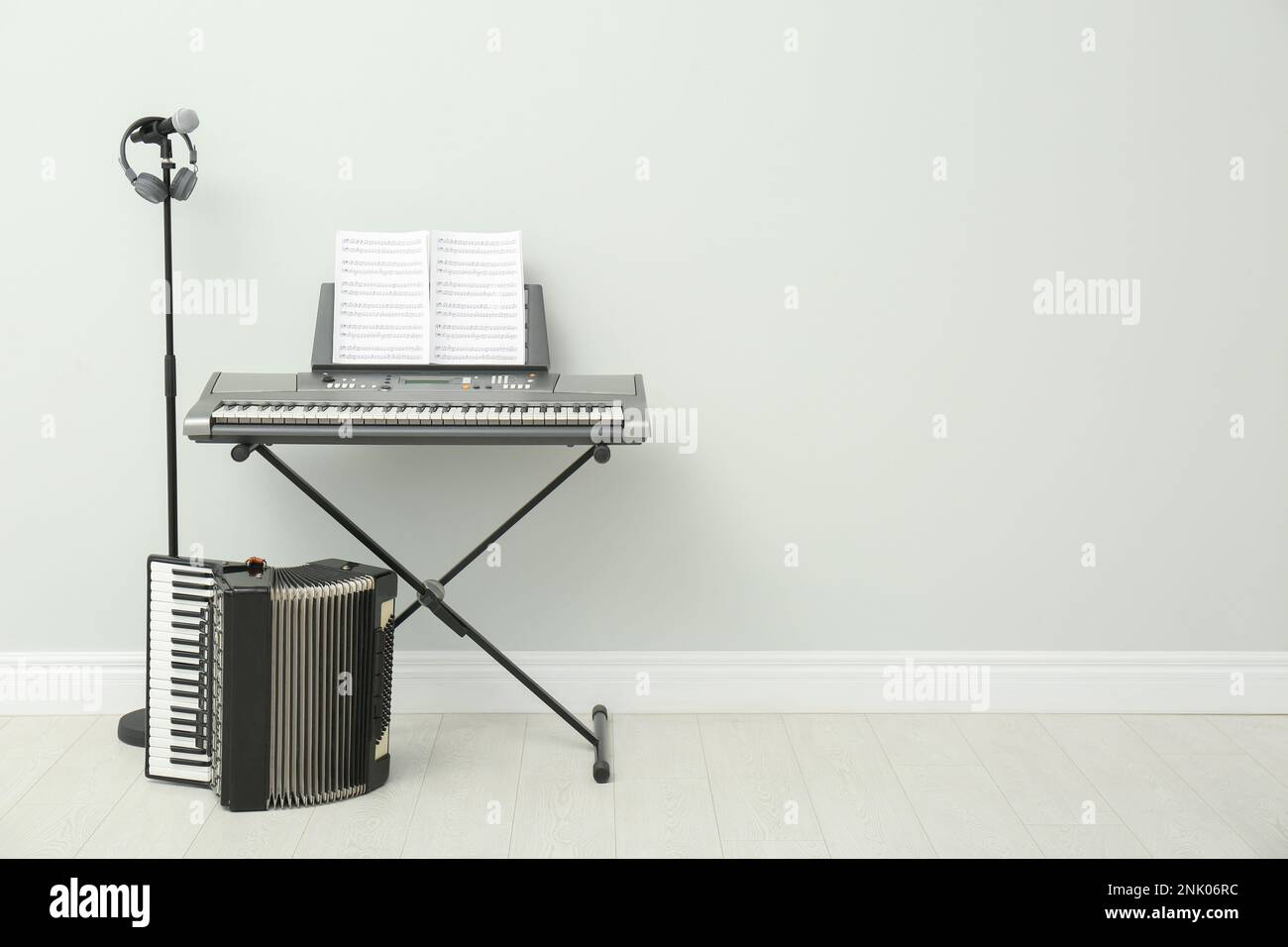 Electronic synthesizer, accordion and microphone near white wall
