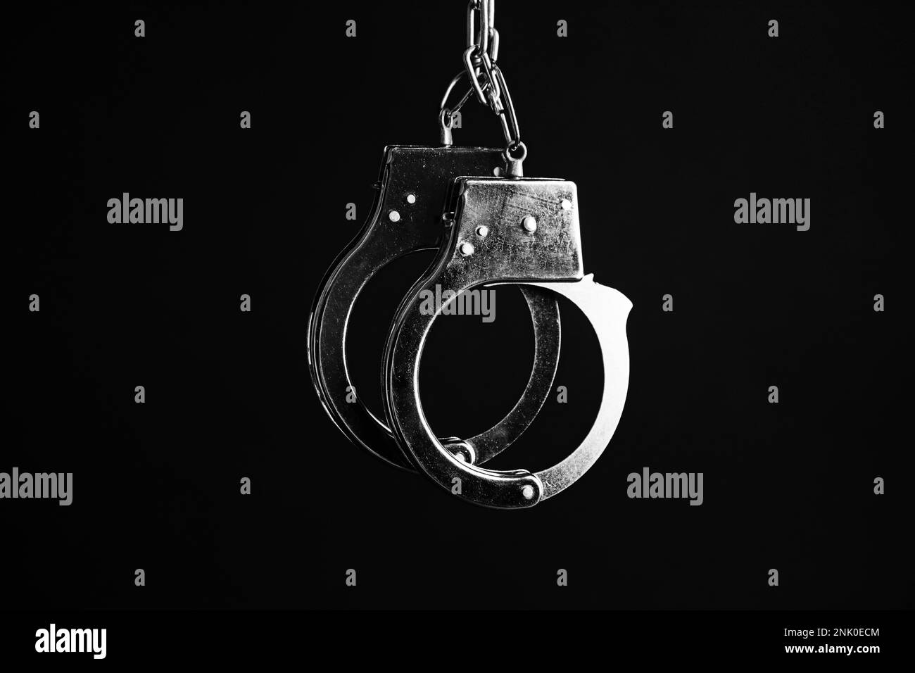Classic chain handcuffs hanging on black background Stock Photo