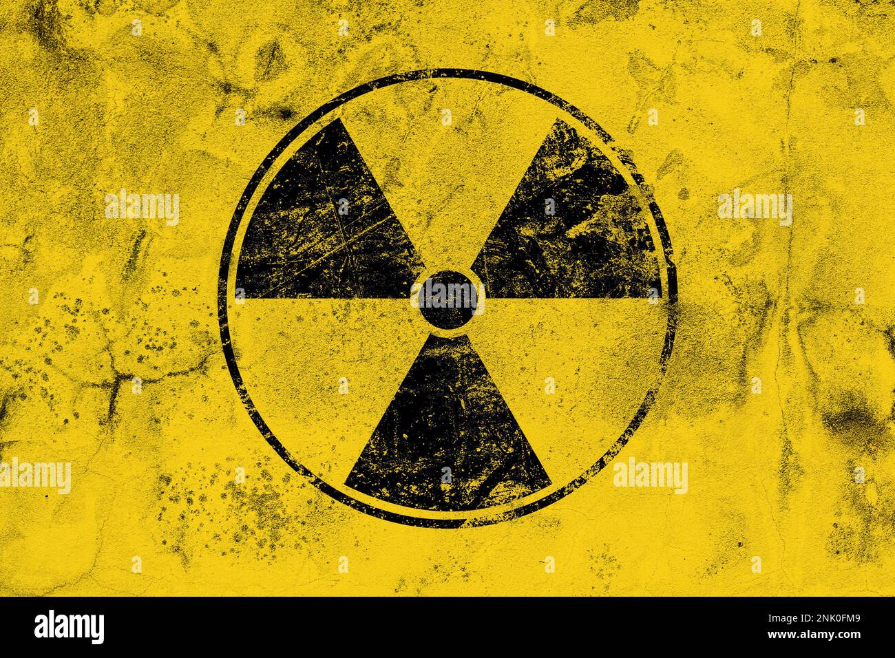 Black radioactive hazard warning sign painted over grunge yellow background with copy space Stock Photo