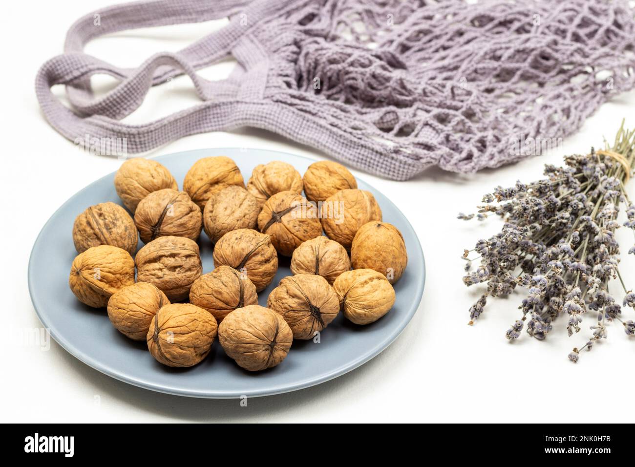 Whole walnuts on a blue plate. Bouquet of dry lavender sprigs. Fabric