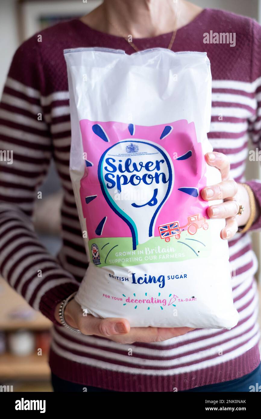 A home baker holding a size unopened 3kg bag of Silver Spoon brand Icing Sugar. also known as confectioners sugar. A quick dissolving sugar Stock Photo