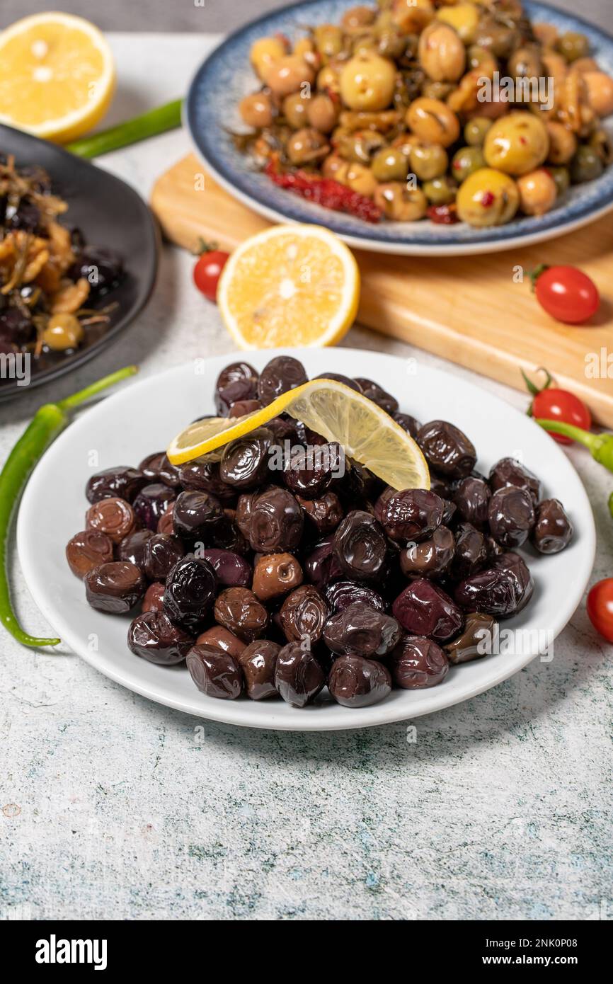 Olive varieties. Assortment of black and green olives on plate on gray background. Close up Stock Photo