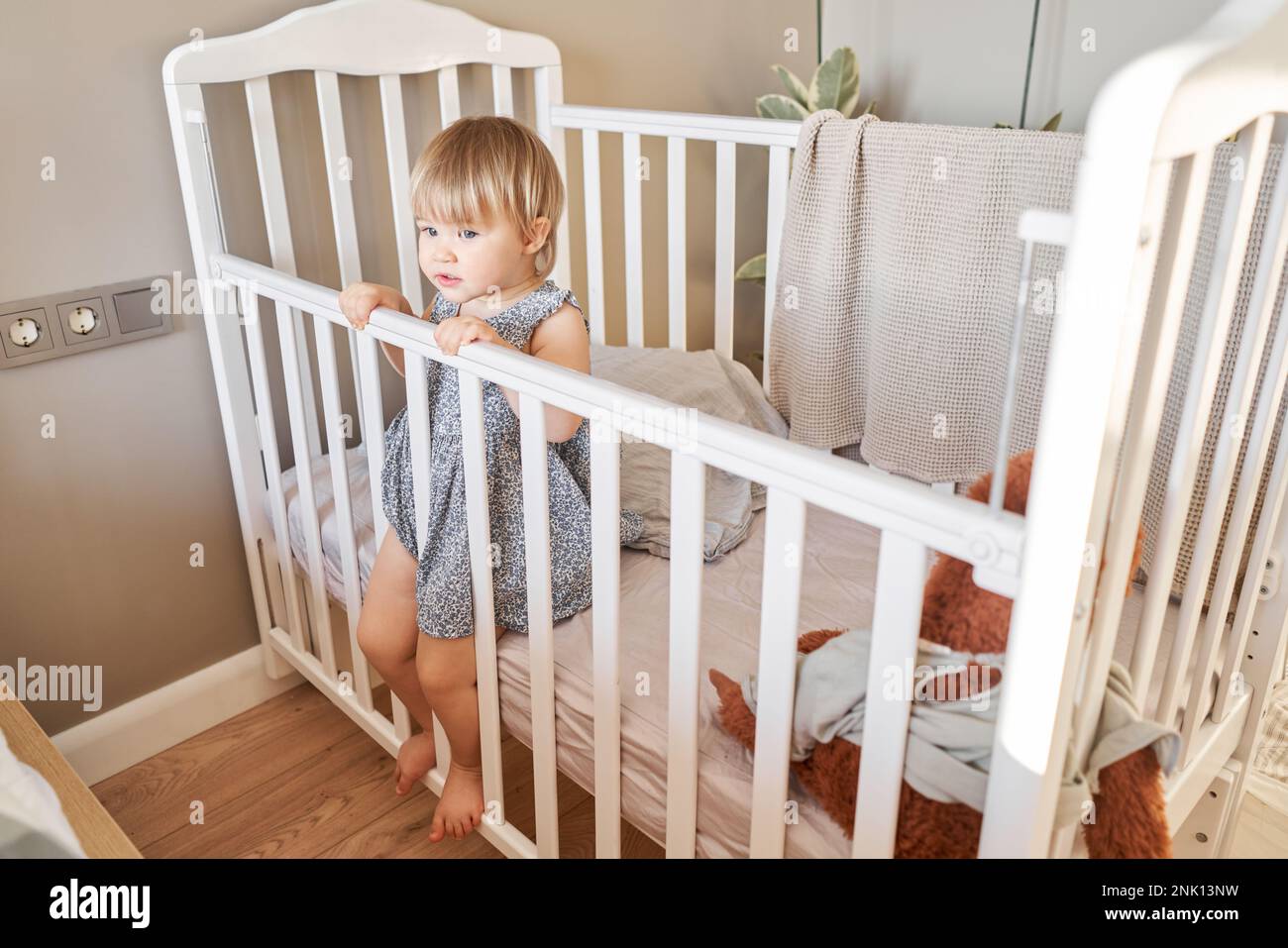 Happy baby girl one and half standing in the crib. Smiling 18 months
