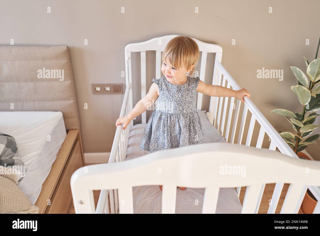 Happy baby girl one and half standing in the crib. Smiling 18 months