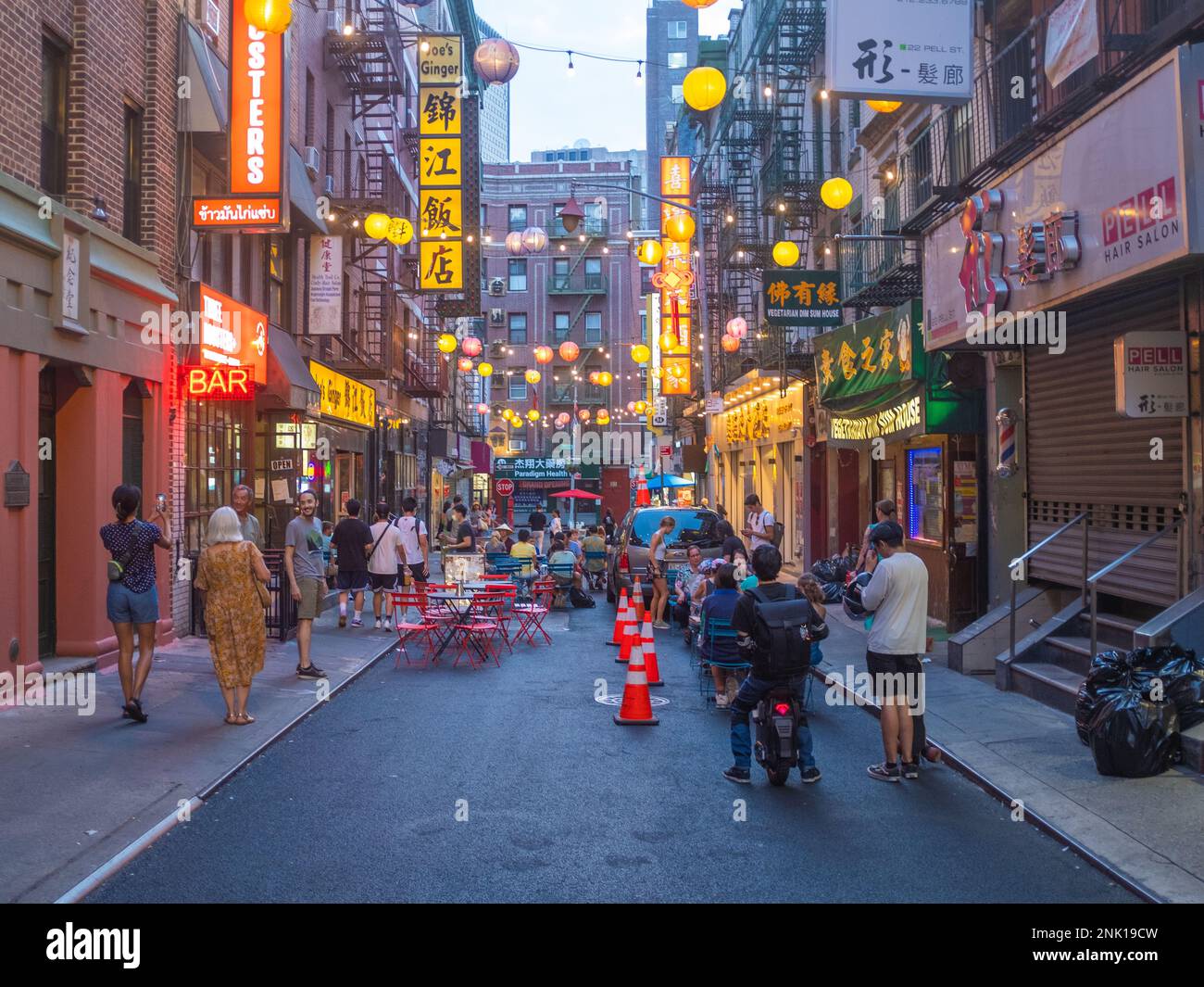 New York City, United States - August 21, 2022: A street of the Chinatown of New York City at dawn with lights and lanterns switched on and some peopl Stock Photo