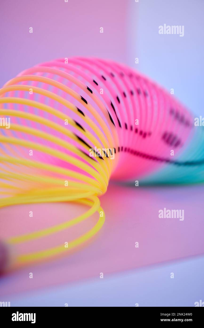 Rainbow, slinky toy and color spiral in studio for neon background for flexible, abstract or creative vaporwave aesthetic wallpaper. Colorful plastic Stock Photo