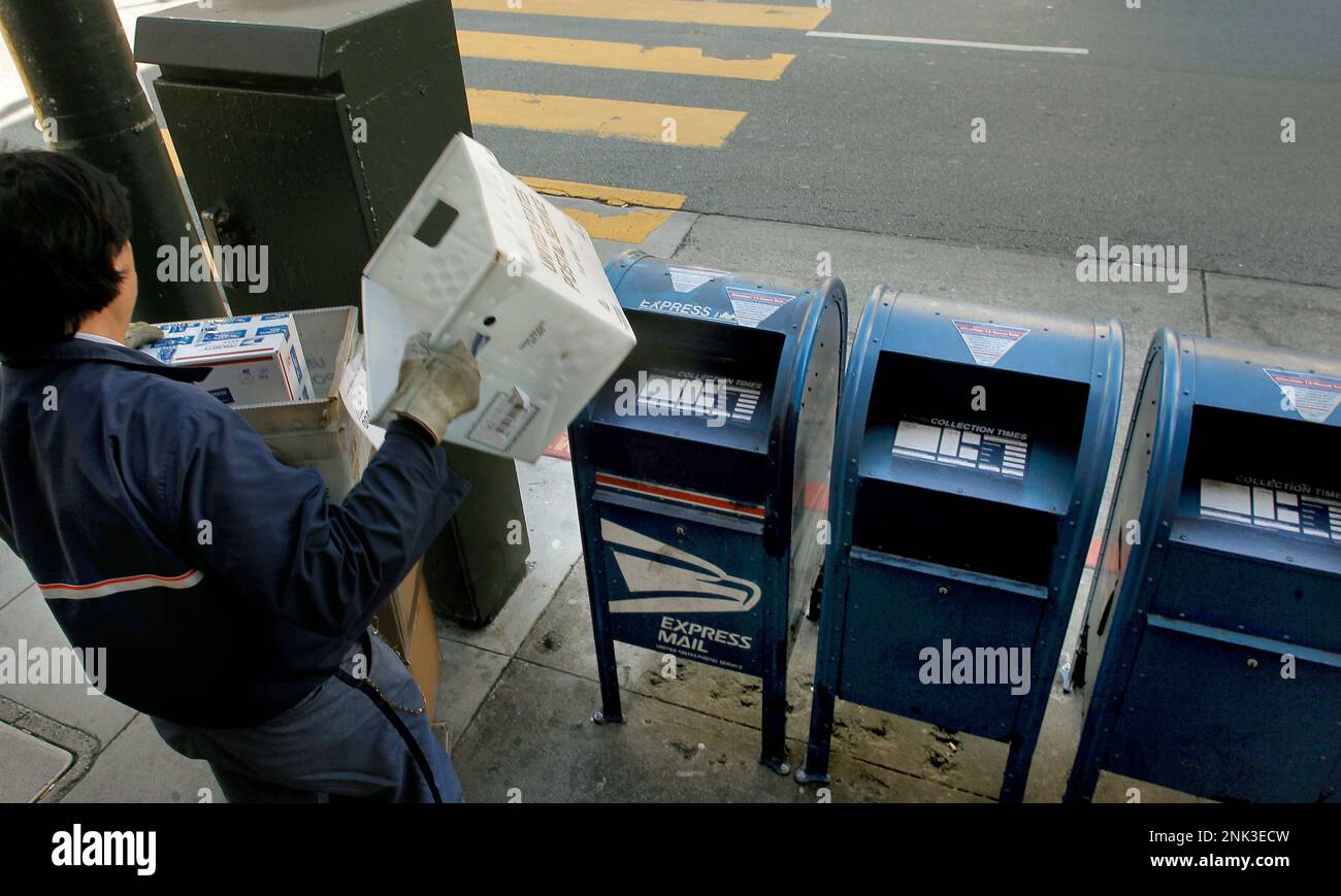 Letter carrier Wilbur Yuen empties the mailboxes in front of the