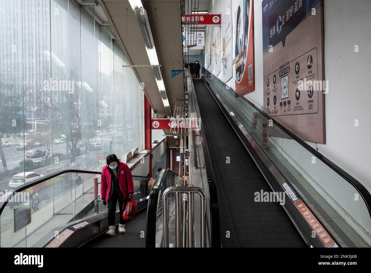 A customer takes an escalator to a Carrefour store in Wuhan. Carrefour entered the Chinese market in the year 1995 and expanded very quickly, securing a large market share. However earnings began to get smaller as the competition kept on increasing. In the year 2019, the French retailer sold around 80% of its 'loss-making' China business to Jiangsu-based 'Suning' for CNY 4.8 billion which was equal to USD 699 million at the time).This month, reports of shortages at the many local Carrefour store have caught the attention of customers. Several people started complaining that they have been unab Stock Photo