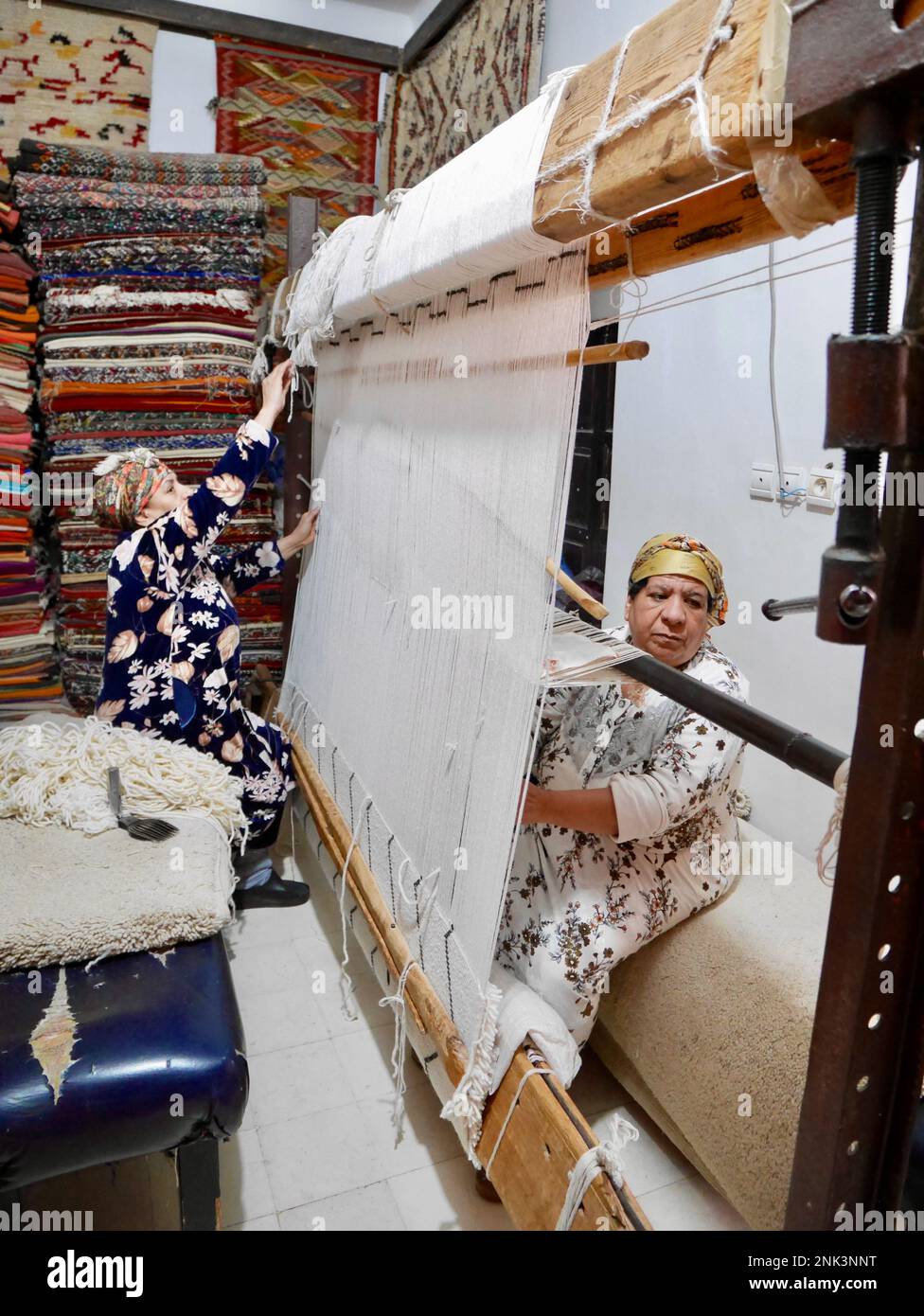 Moroccan women weaving Berber carpet in rug shop in Medina of Marrakech