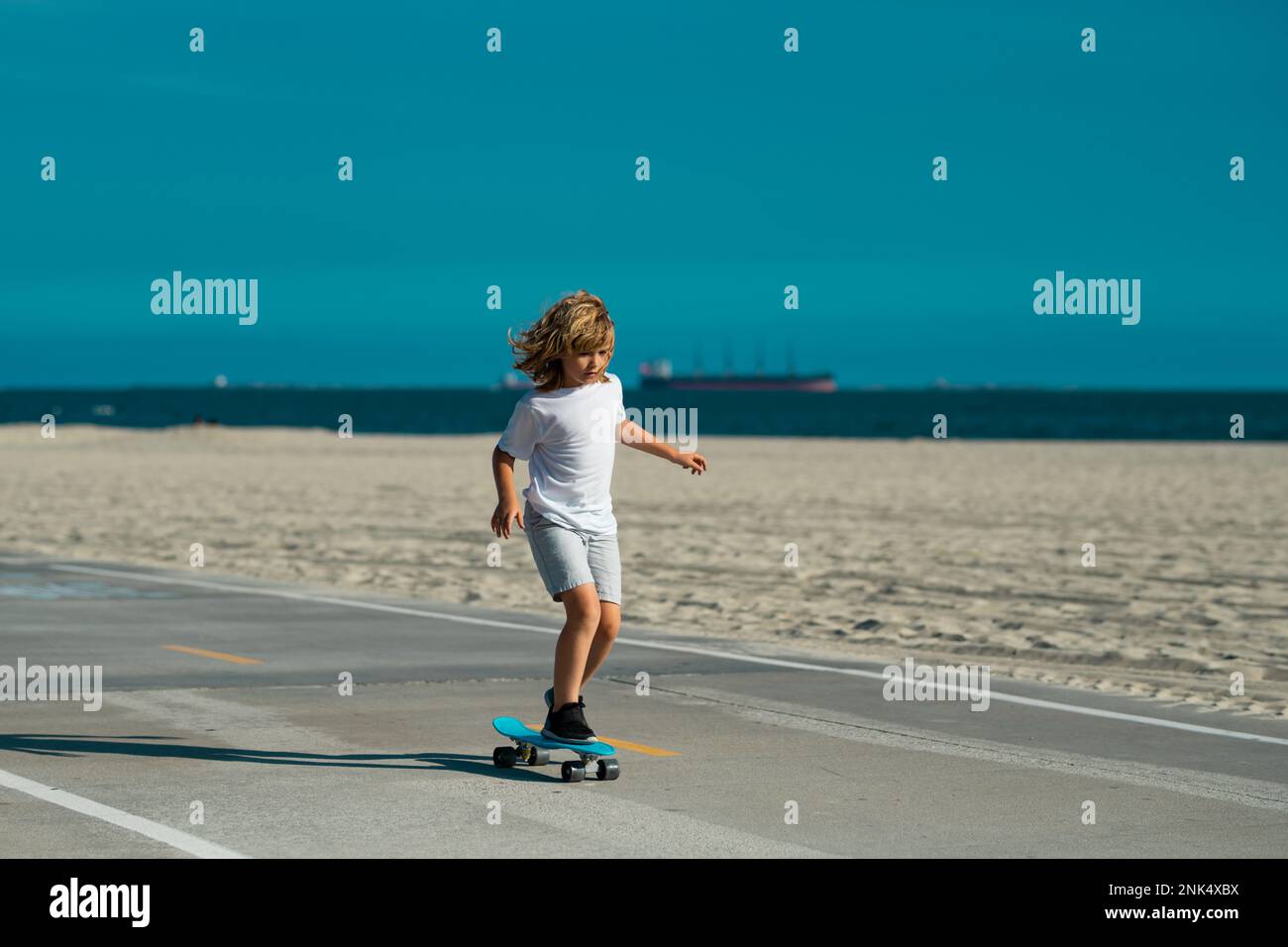 Kid skateboarder ride a skateboard on street. Child in a summer city