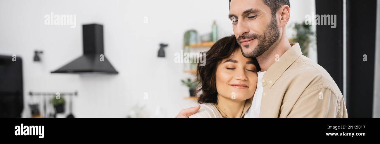 Bearded man hugging smiling wife at home, banner Stock Photo - Alamy