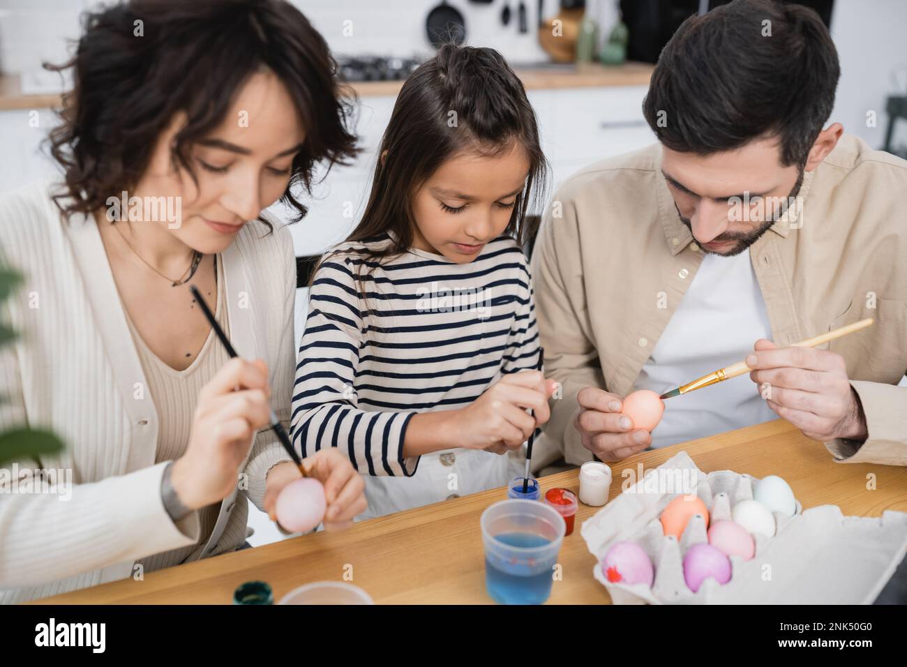 parents and child painting Easter eggs in kitchen Stock Photo