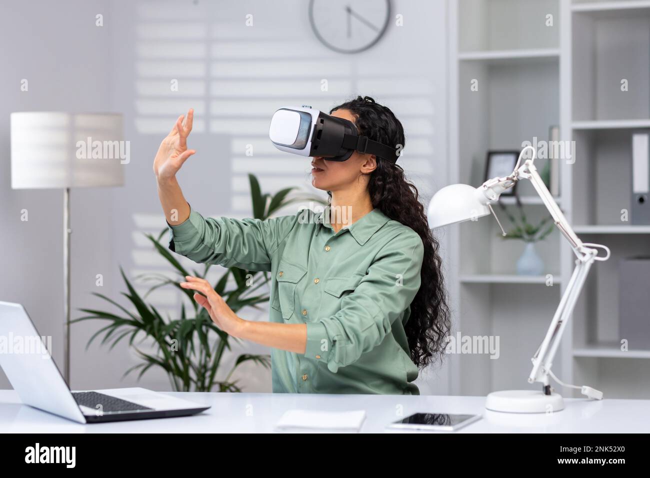 Young successful woman inside the office using vr glasses virtual reality simulator cross charts and documents online latin american woman using laptop at work Stock Photo Alamy