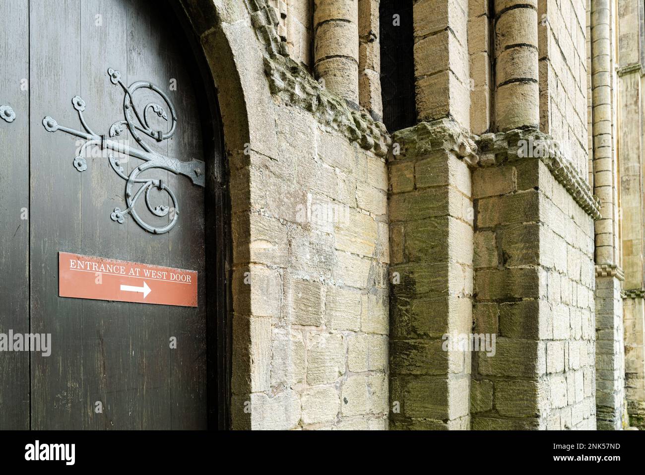 Shallow focus of a sign on a crypt door informing visitors to use the main cathedral entrance. Stock Photo