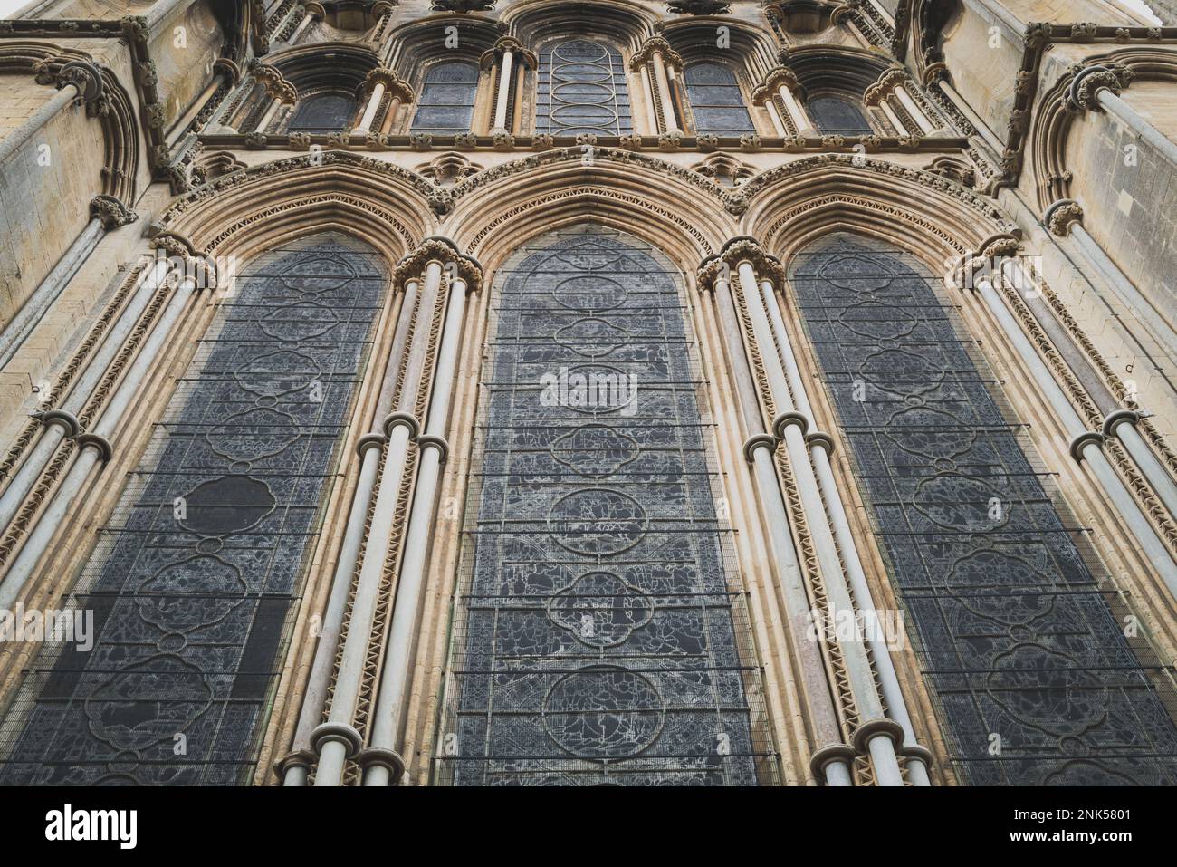 Dramatic vertical view of a historical cathedral showing the huge stained glass windows and ornate stonework. Stock Photo