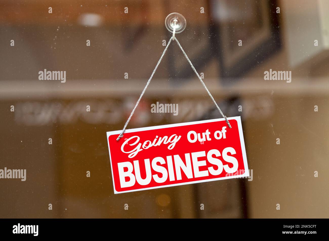 Red sign hanging at the glass door of a shop saying: 'Going out of business'. Stock Photo