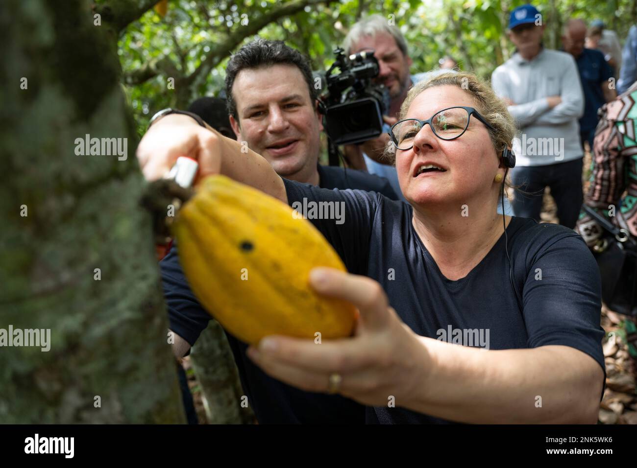 Agboville, Ivory Coast. 23rd Feb, 2023. Svenja Schulze (SPD), Federal Minister for Economic Cooperation and Development, harvests a ripe cocoa pod on a cocoa plantation. Behind her is Hubertus Heil (SPD), Federal Minister of Labor and Social Affairs. Federal Minister of Labor Heil and Federal Minister for Economic Cooperation and Development Schulze visit Ghana and Côte d'Ivoire. Credit: Christophe Gateau/dpa/Alamy Live News Stock Photo