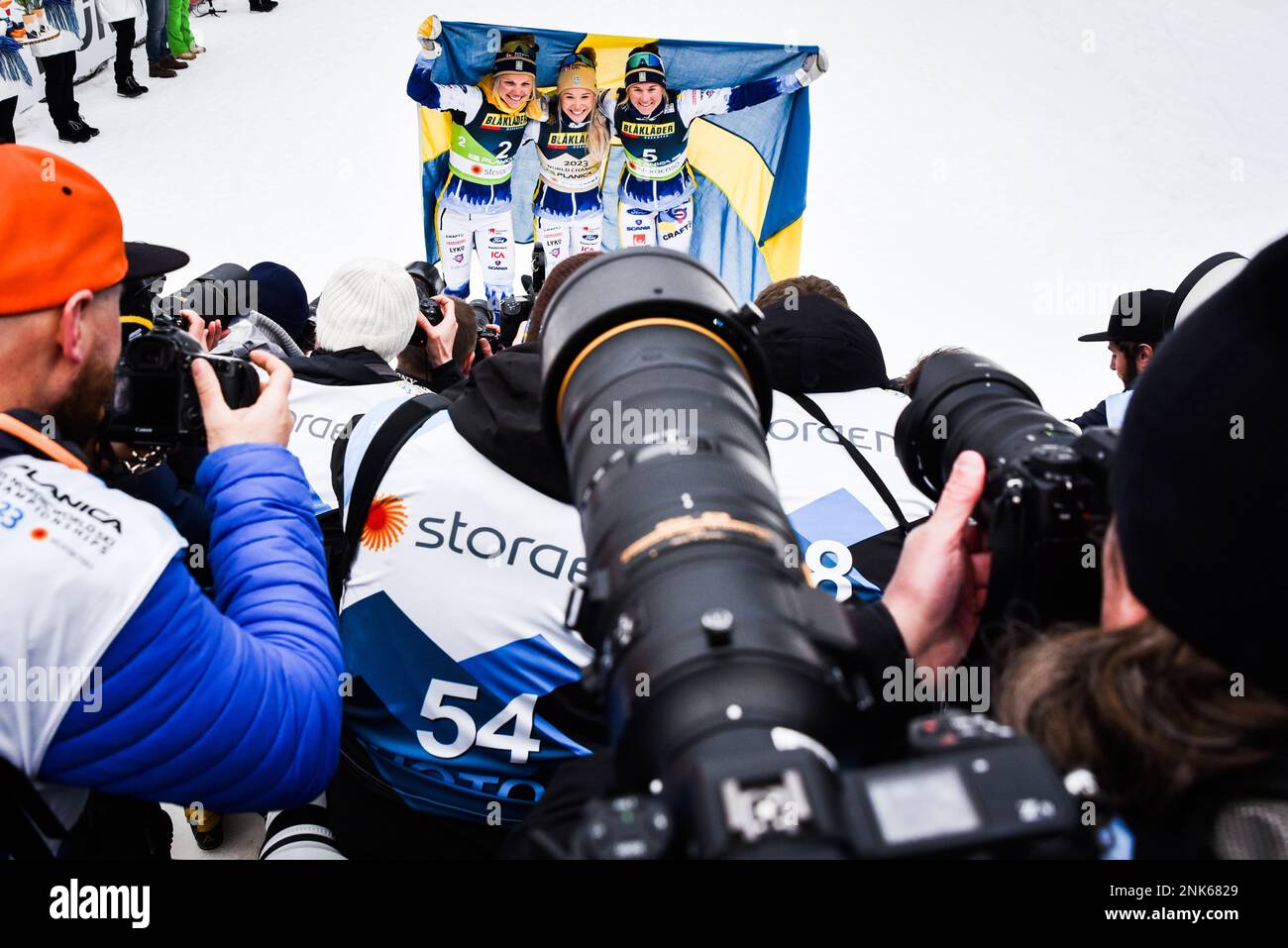 Planica, Slovenia, February 23, 2023. Photographers close in as Swedish woman celebrate after sweeping the podium in the sprint at the 2023 FIS World Nordic Ski Championships in Planica, Slovenia, February 23, 2023. From left, Emma Ribom (2nd), Jonna Sundling (first), and Maja Dahlqvist (third). Stock Photo