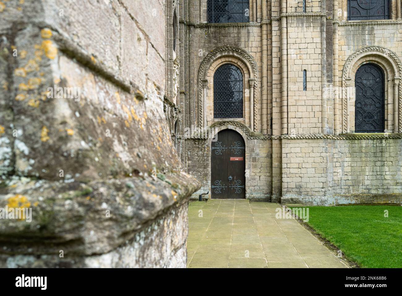 Distant focus of a wooden door, with entry to the cathedral crypt. The red sign on the door informs visitors to use another door. Stock Photo
