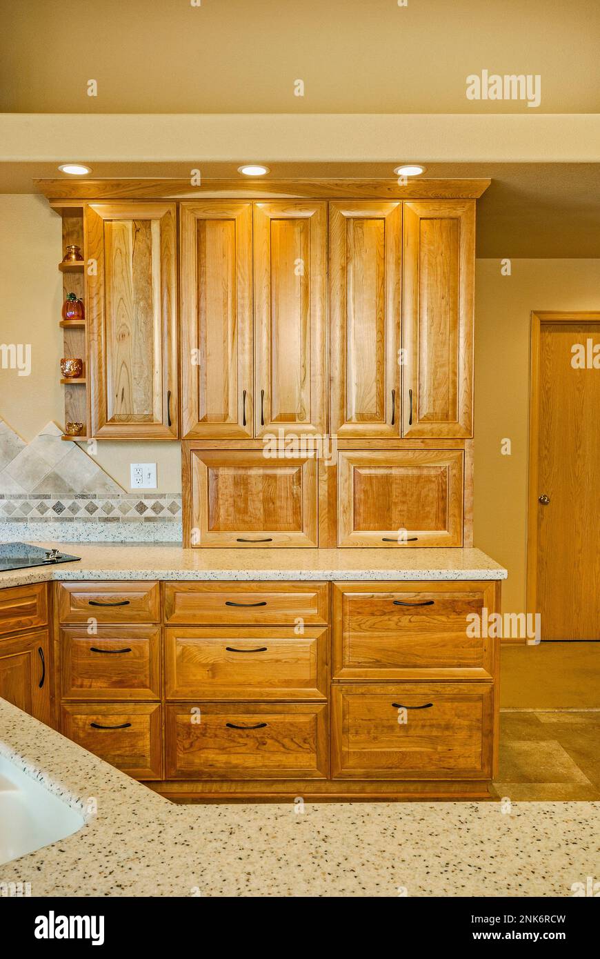 Wood doors, drawers, shelves, and a light stone countertop are