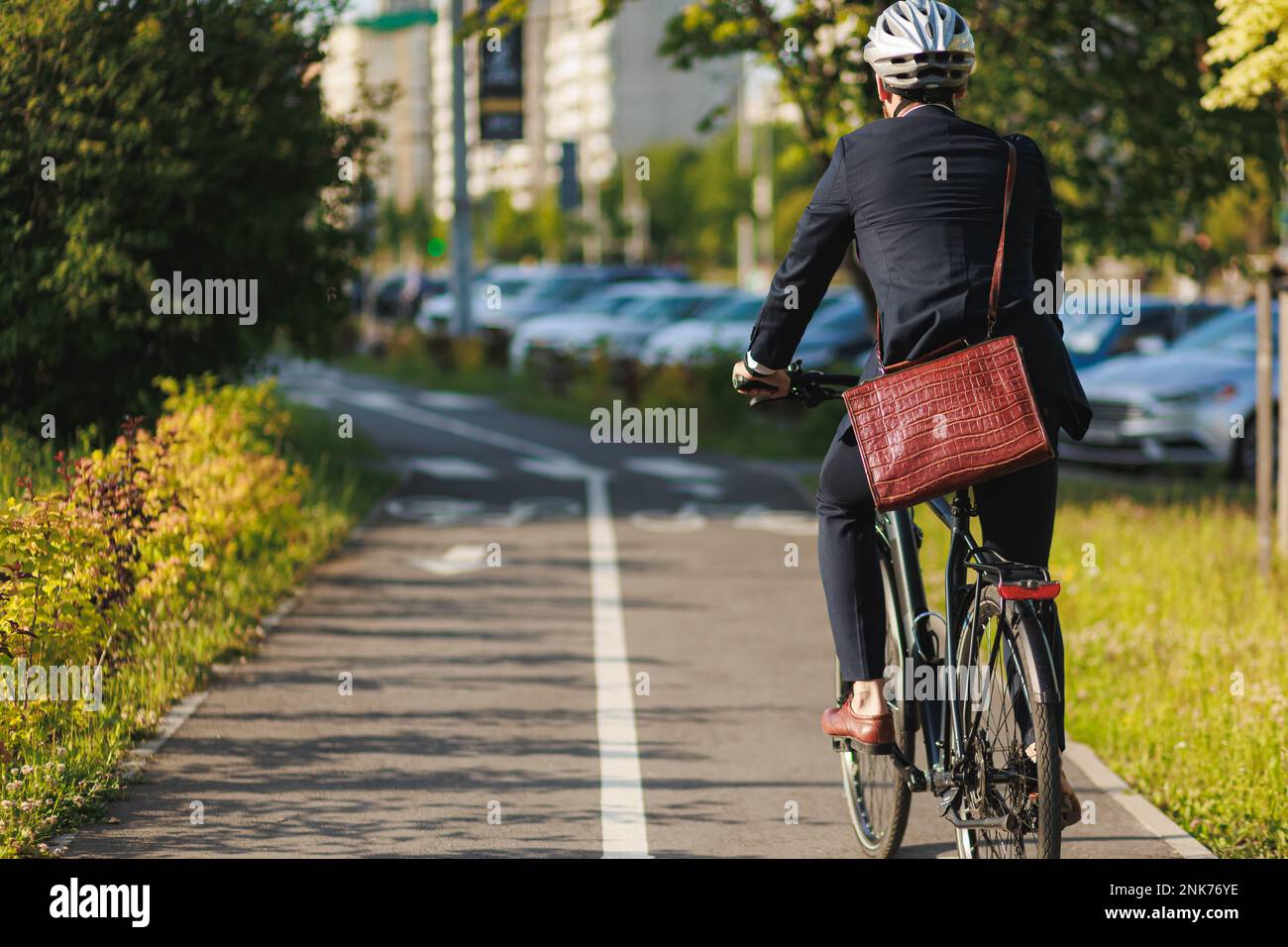 Elegant entrepreneur in smart casual cycling on bicycle track in warm ...