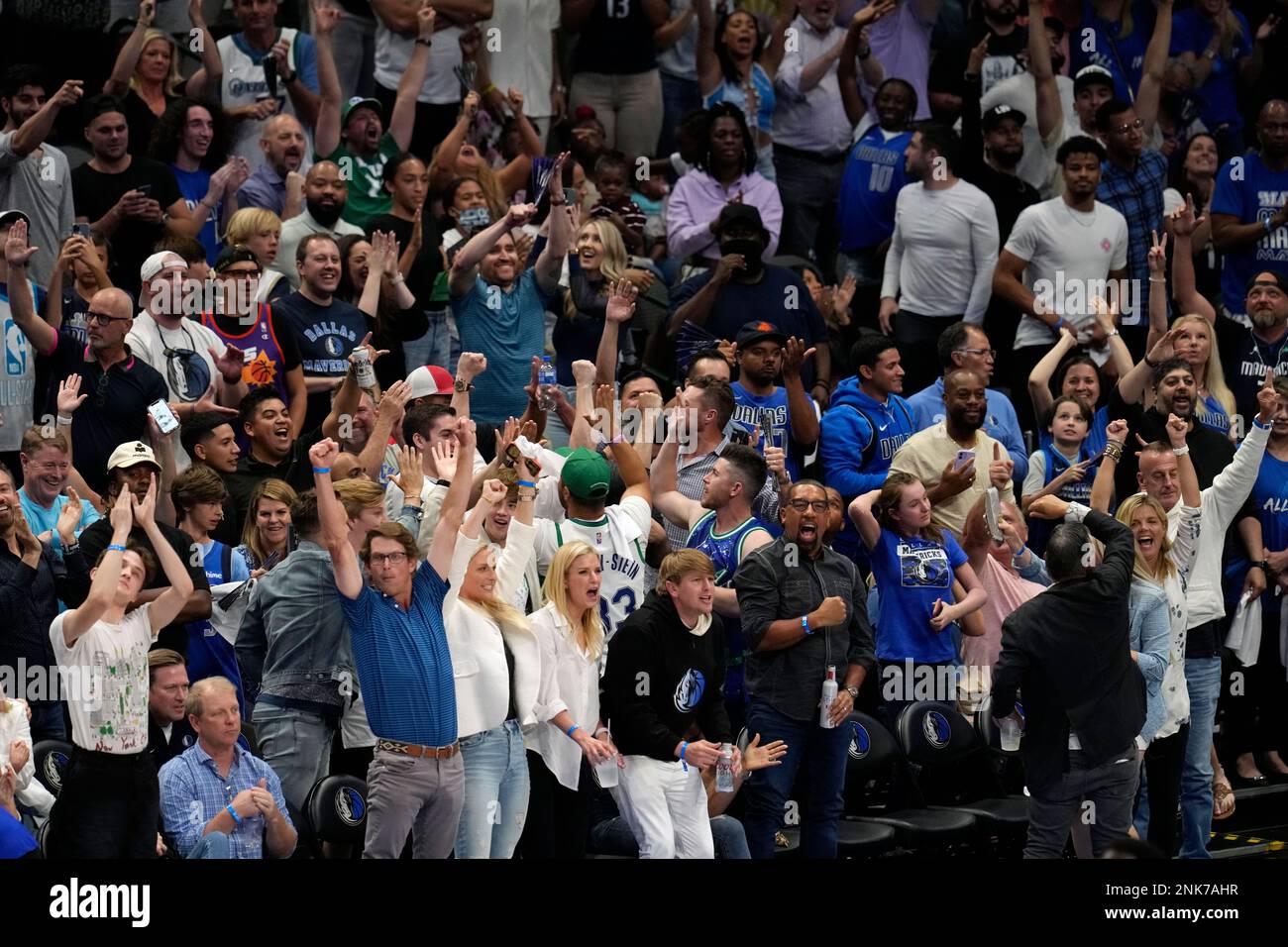 A large group or section of Dallas Mavericks fans cheer and celebrate