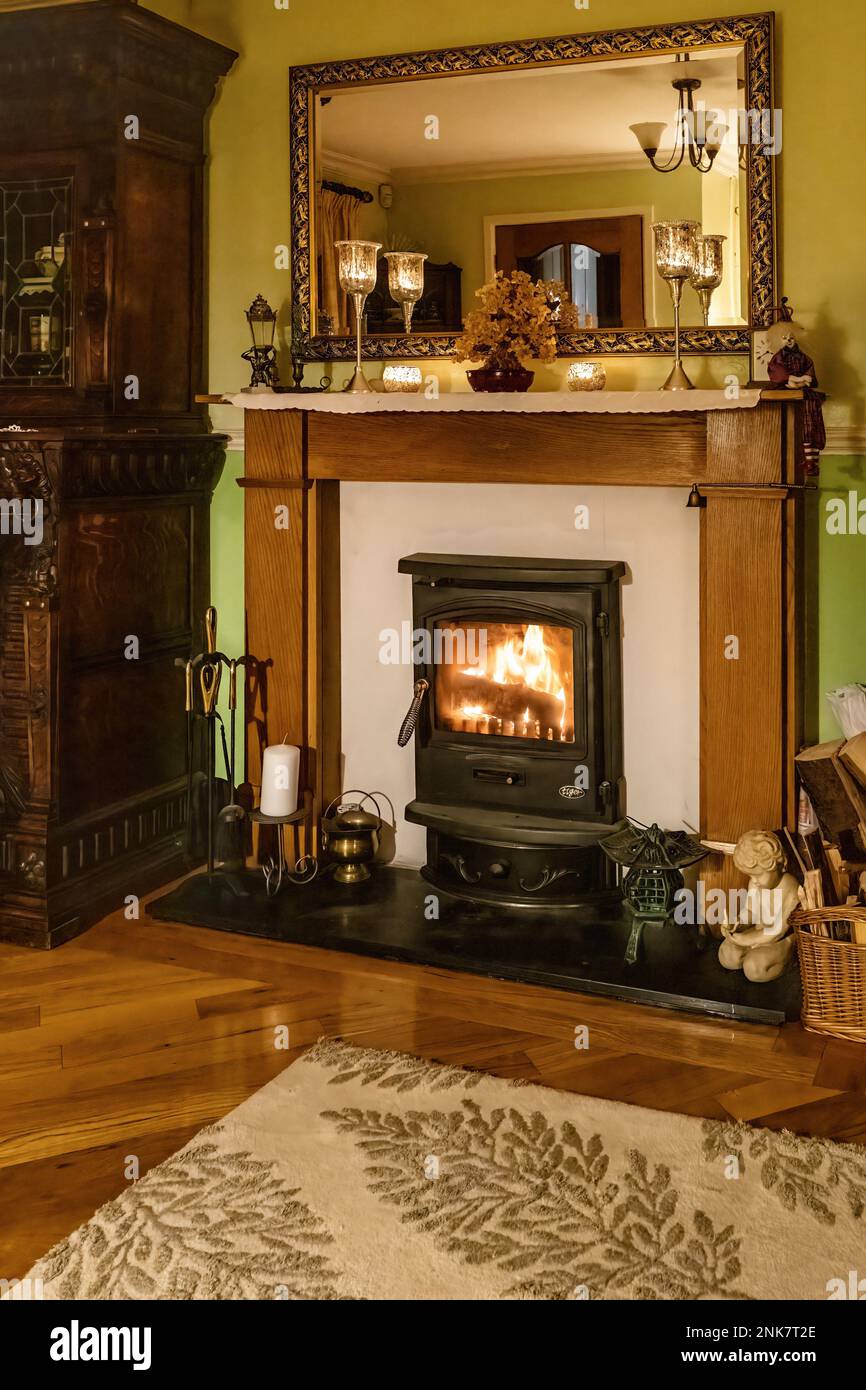Cosy winter living room fireplace, with wood burning stove, UK home interior with antique furnishings. Stock Photo