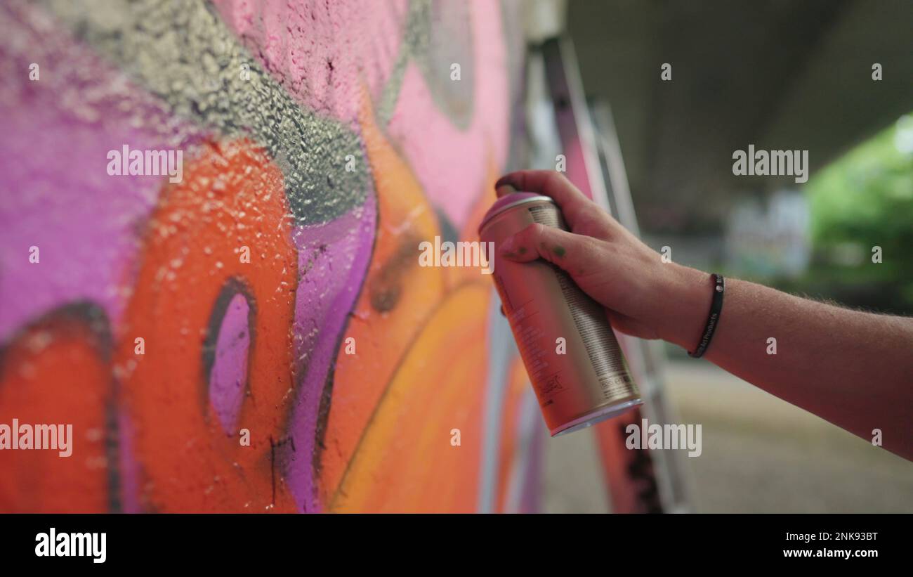 Spray Paint Wall Graffiti Art. person spray painting on a wall in the