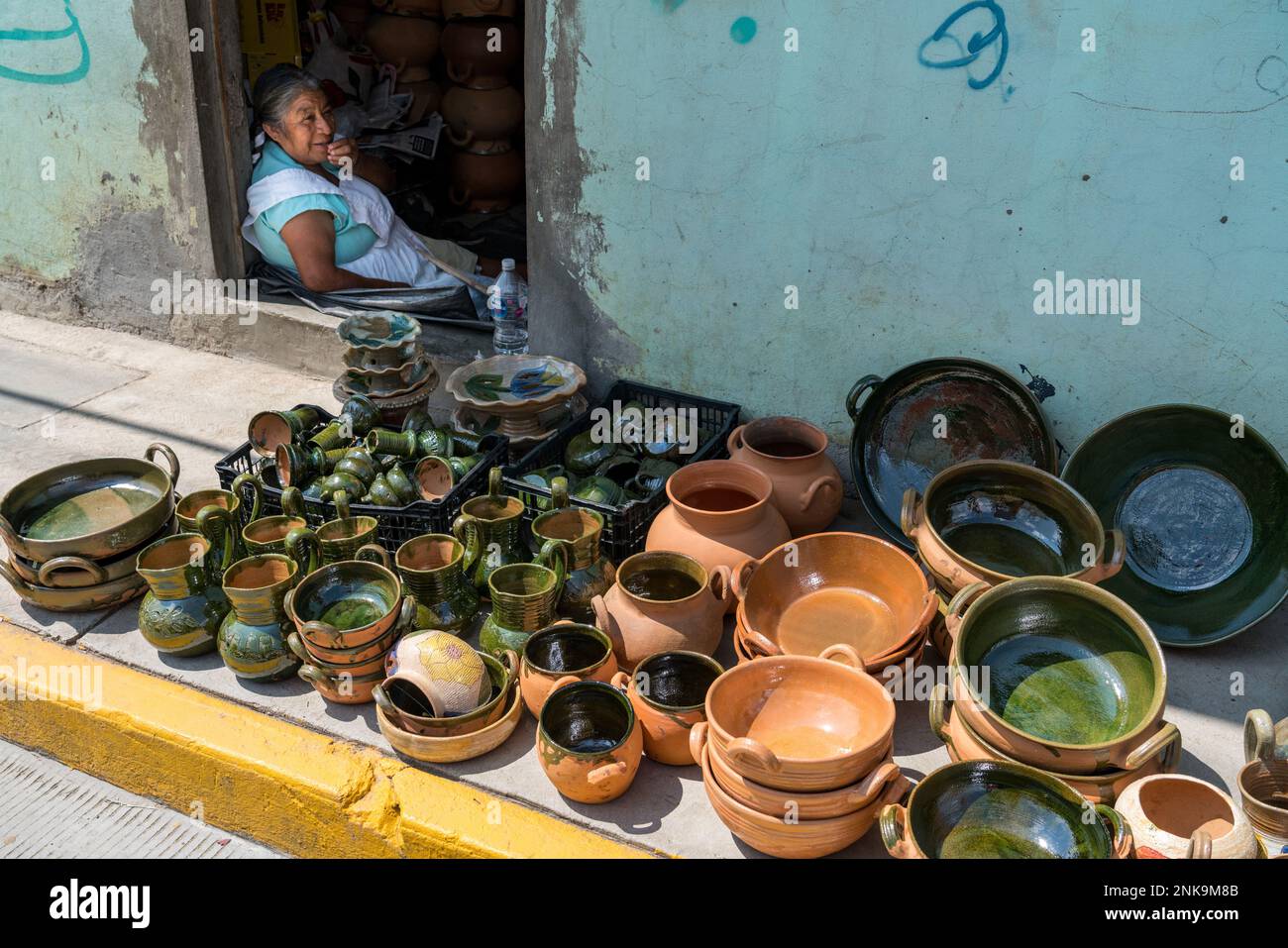 An indigenous Zapotec woman sits in the doorway of her house and sells