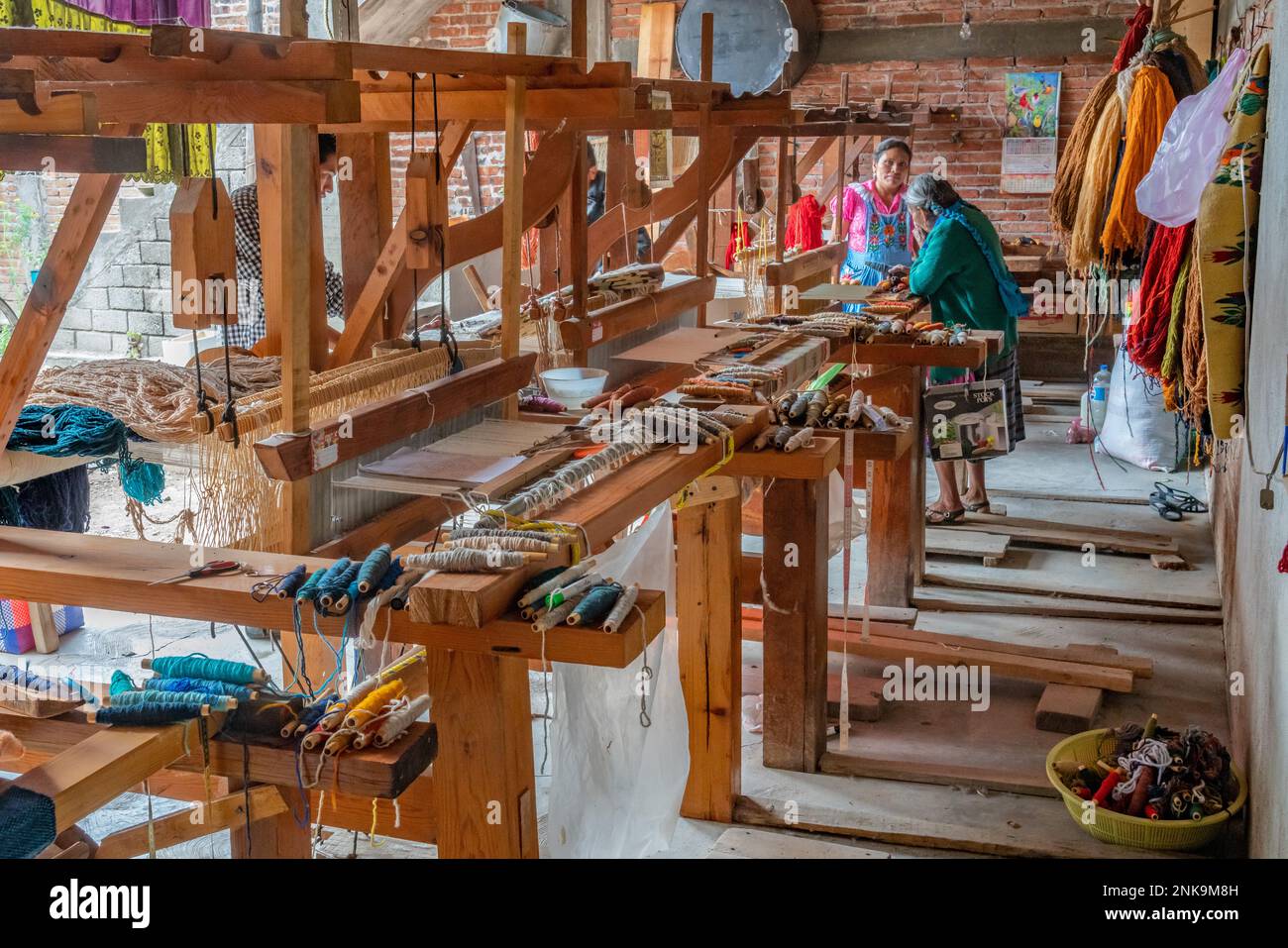 Two indigenous Zapotec women and a row of wooden footpedal looms in a