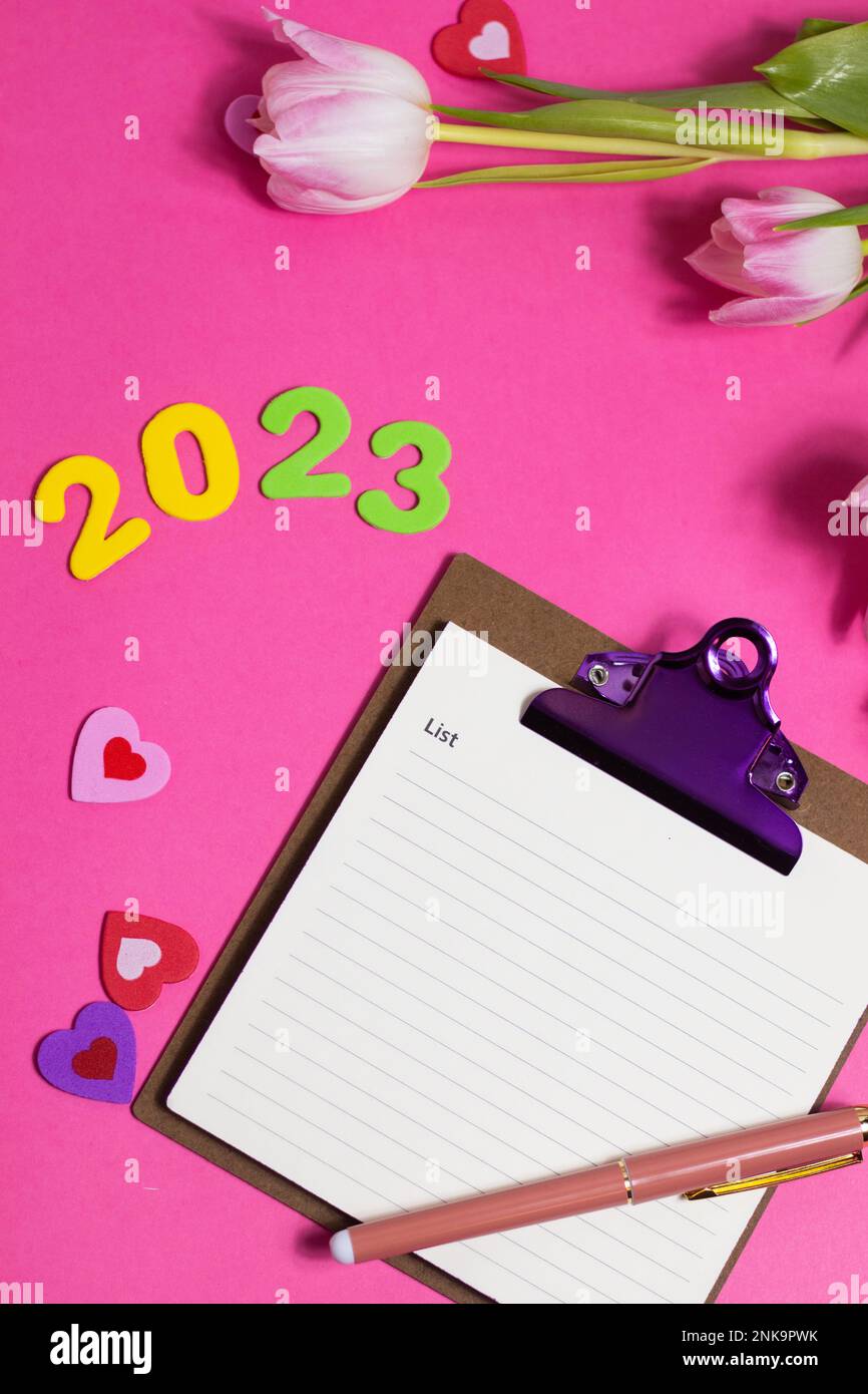Composition with blank, 2023 and beautiful tulip flowers on pink background Stock Photo