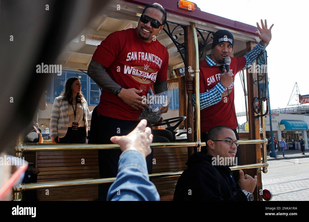 A fan at Fisherman's Wharf poses in front of Jimmy Uso (left) and Jey Uso  while they ride on a cable car through San Francisco, Calif. Friday, March  27, 2015 to promote