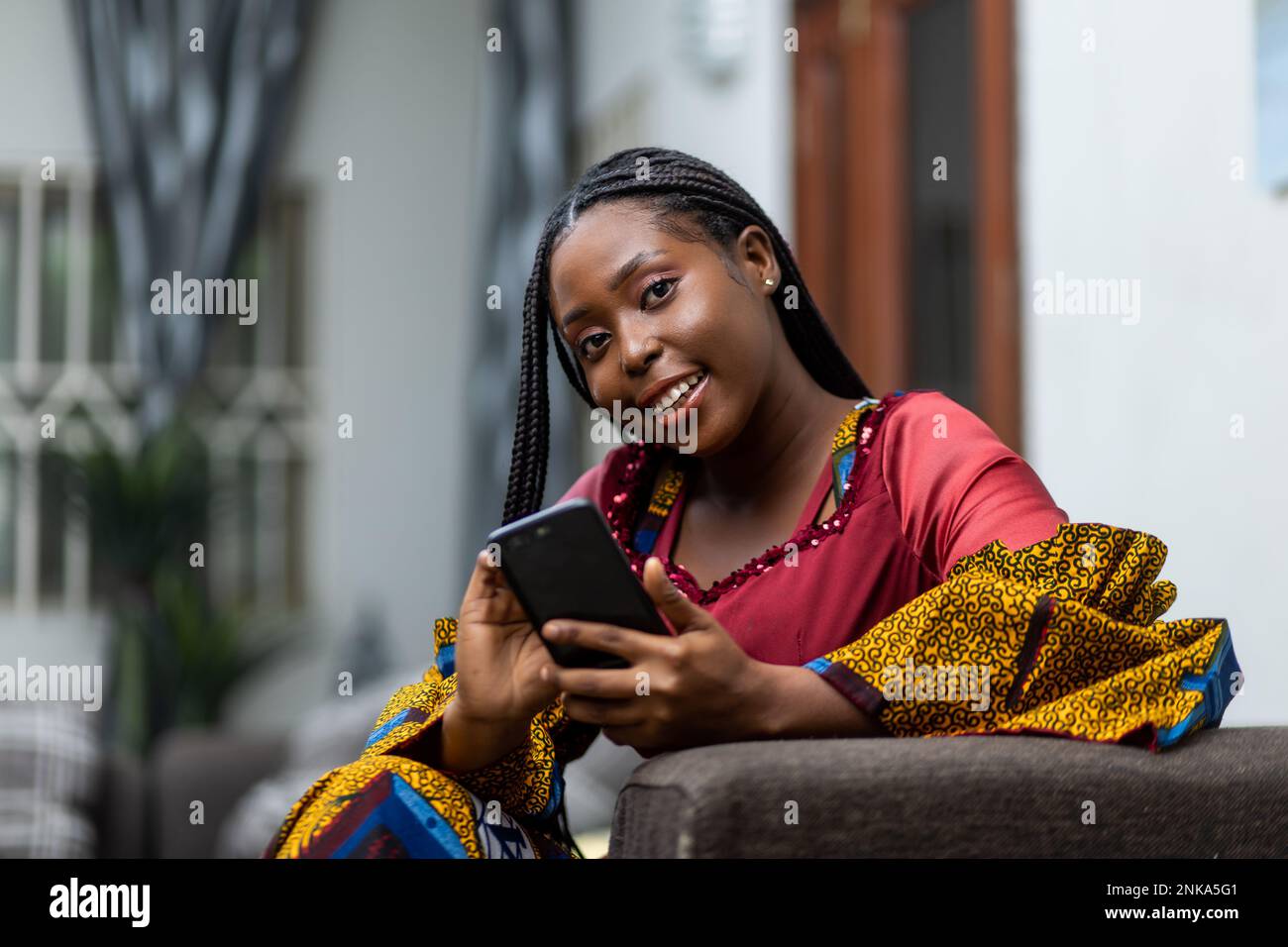 African Woman holding smartphone smiles at camera Stock Photo - Alamy