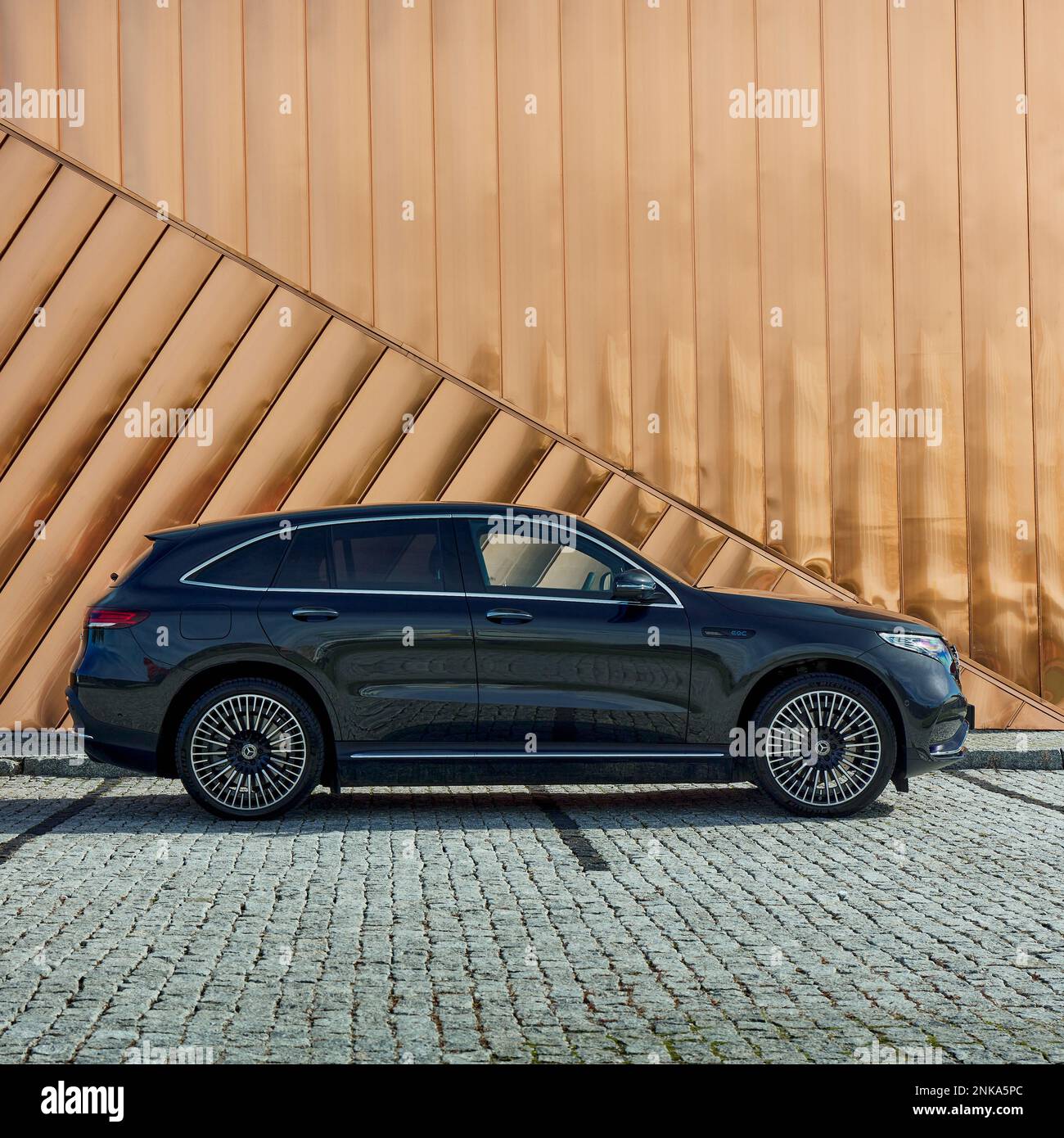 Electric Mercedes EQC standing against the golden wall of the Fire Museum. The car has a 408HP engine and accelerates 0-100 km-h in 5.1 seconds. Range Stock Photo