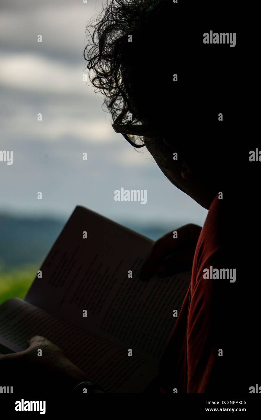 The author is reading a book while sitting in the mountain zoom house. Photo taken from Bandarban, Chittagong, Bangladesh. 8 March, 2022. Stock Photo