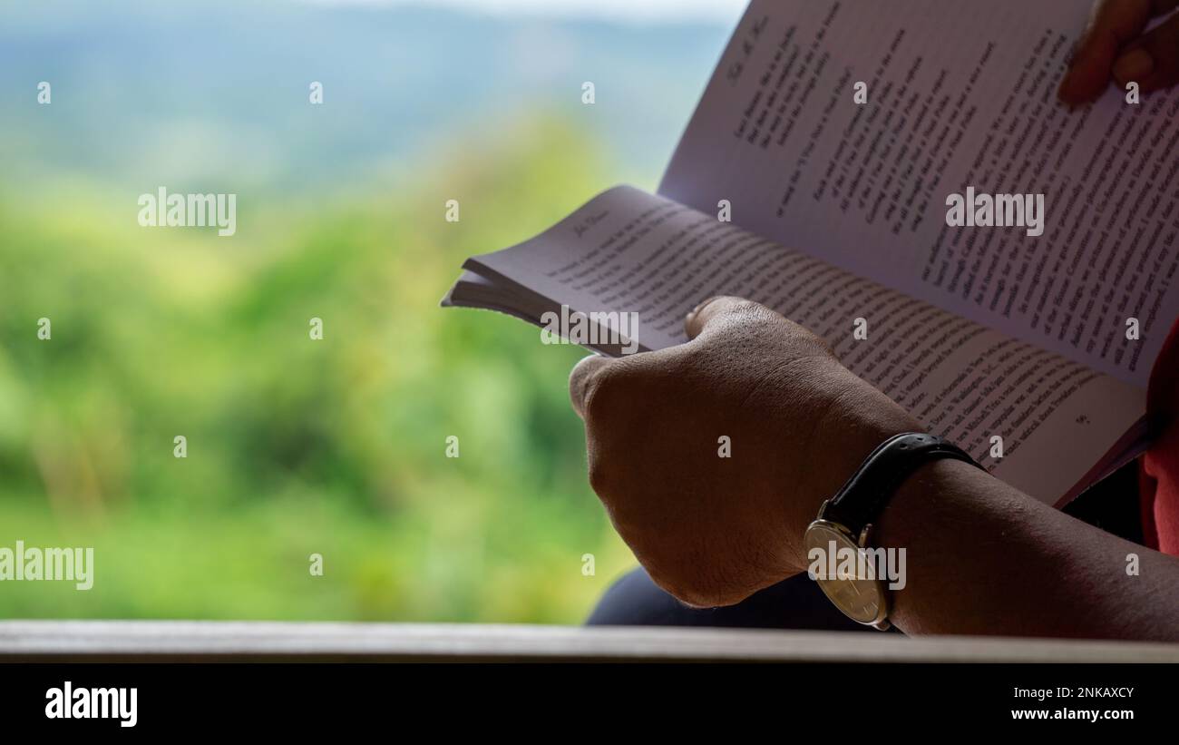 The author is reading a book while sitting in the mountain zoom house. Photo taken from Bandarban, Chittagong, Bangladesh. 8 March, 2022. Stock Photo